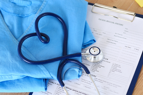 Medical stethoscope twisted in heart shape lying on patient medical history